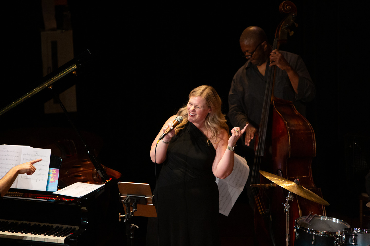 The band's vocalist singing joyfully into the mic, pianist and upright bassist beside her.