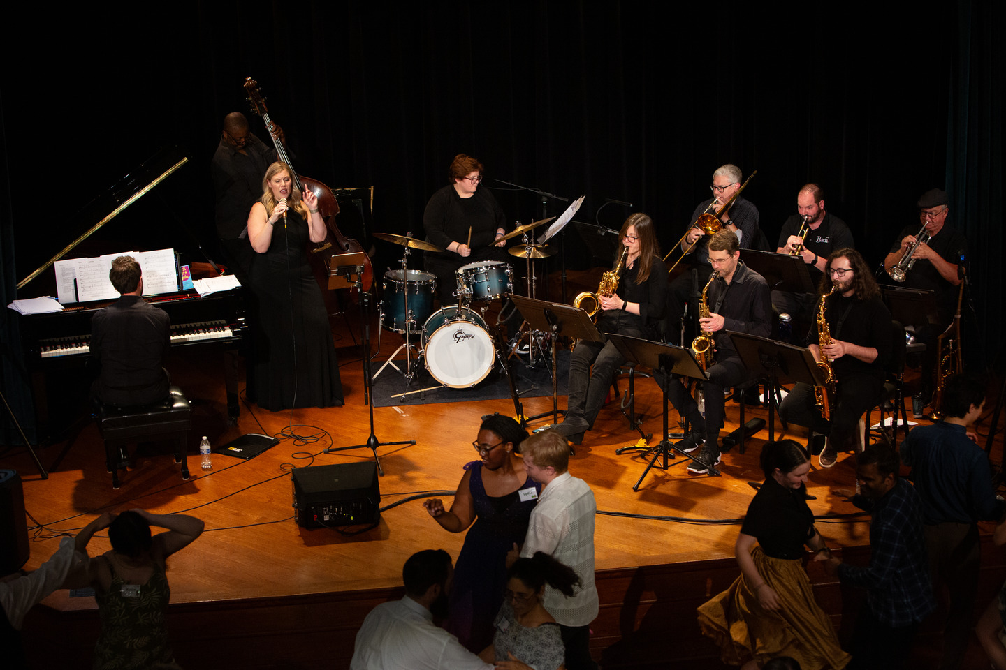 An elevated view of the whole band performing while couples dance just below the stage.